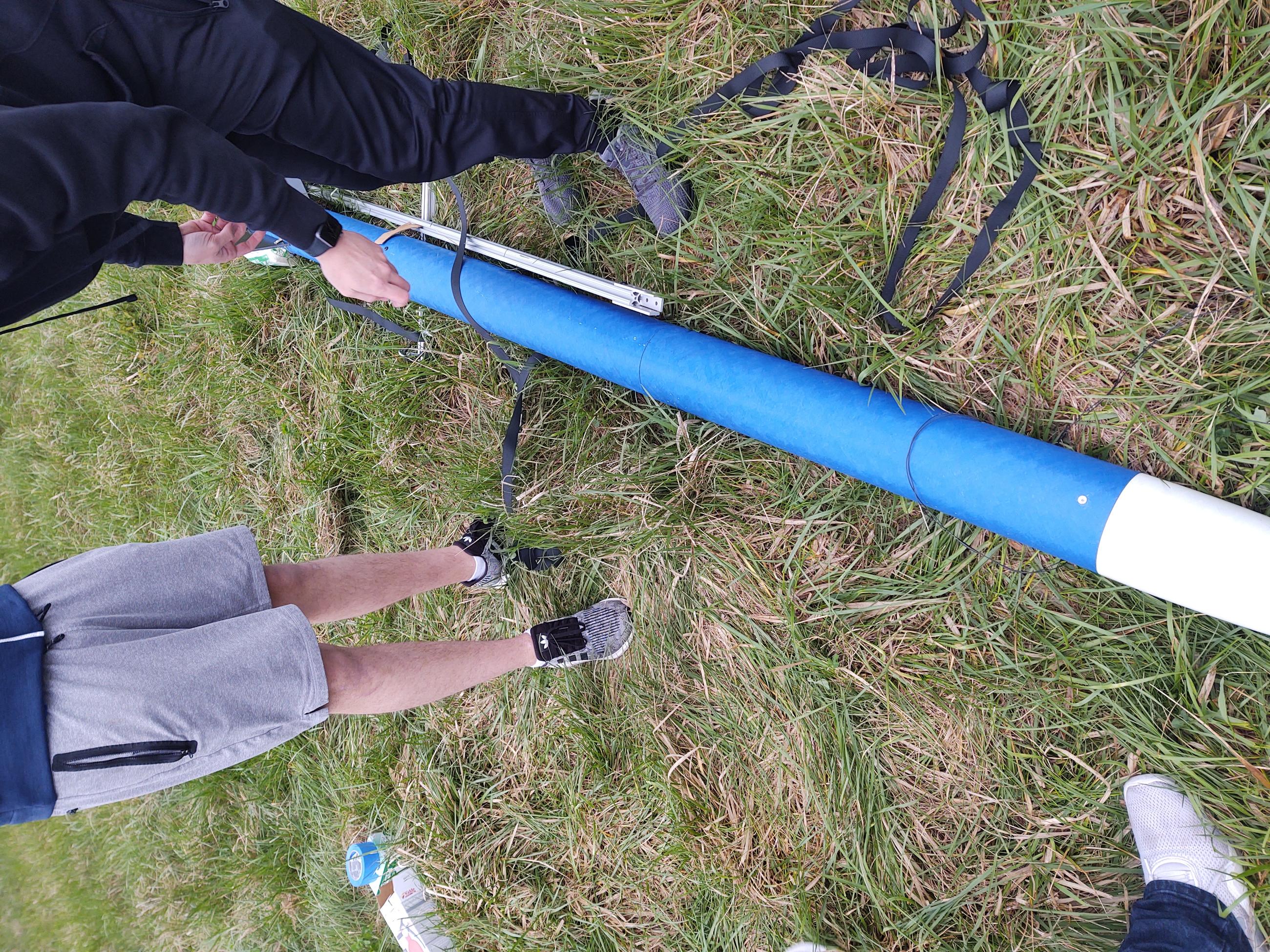 Model rocket laying in the grass with two people standing on either side